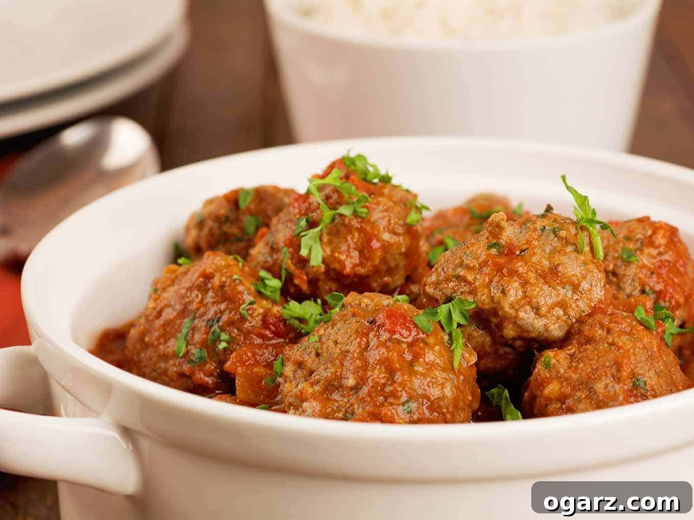 Moroccan lamb meatballs in spiced tomato sauce, garnished with parsley and served in a white bowl.