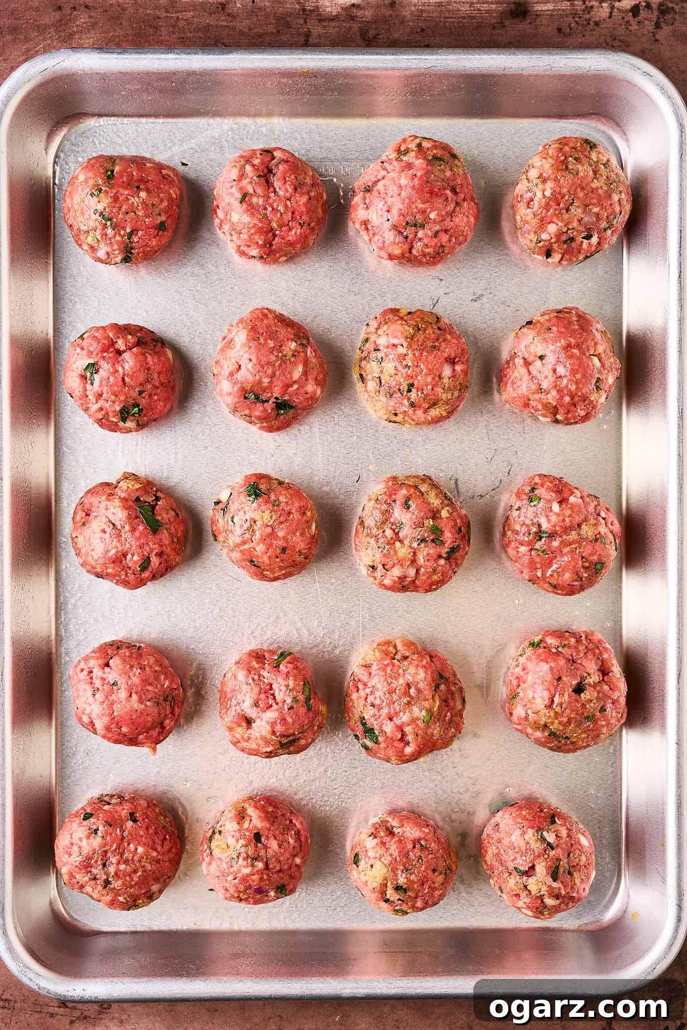 Soutzoukakia: Flavorful Greek Meatballs in Rich Tomato Sauce 7 Greek meatballs on a baking sheet, ready for the oven.