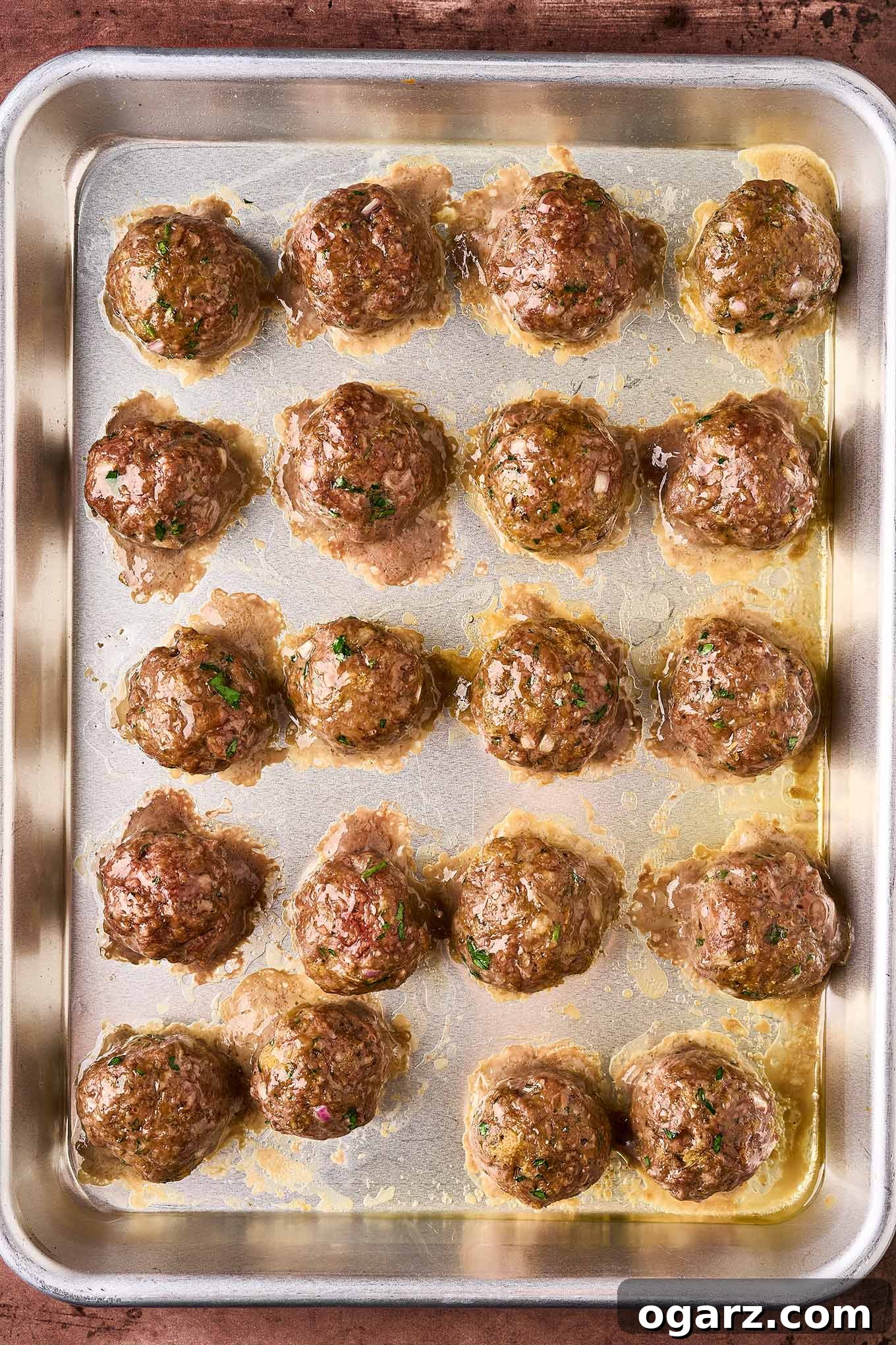 Soutzoukakia: Flavorful Greek Meatballs in Rich Tomato Sauce 8 A sheet pan filled with Greek meatballs, baked until browned and ready to finish cooking in tomato sauce for added flavor.