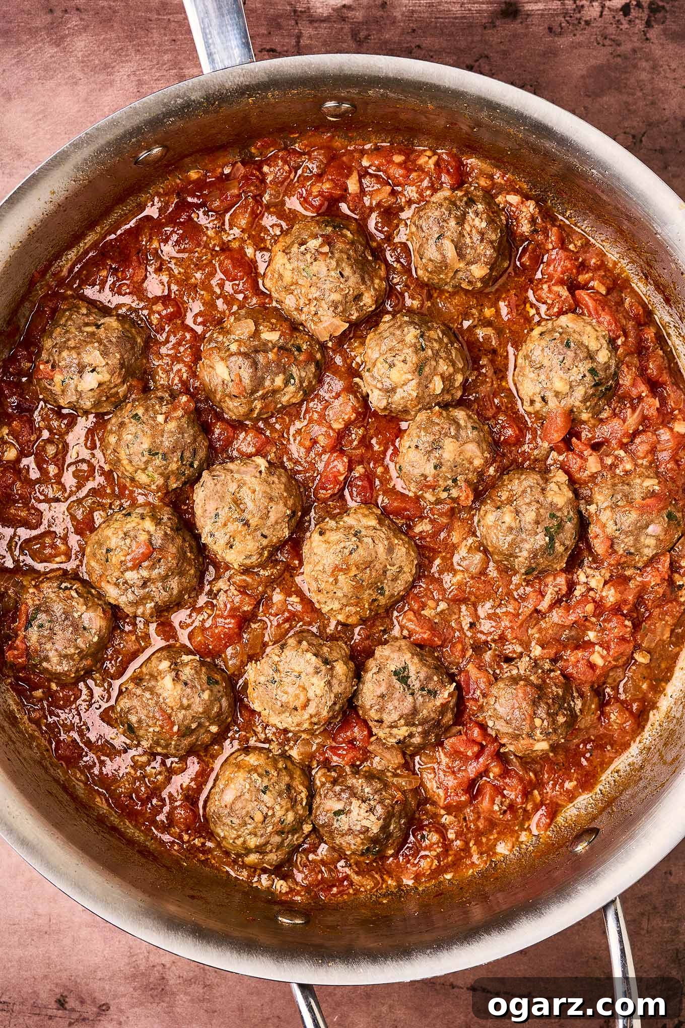 Soutzoukakia: Flavorful Greek Meatballs in Rich Tomato Sauce 9 An overhead view of Greek meatballs simmering in tomato sauce.