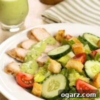 Slices of grilled turkey tenderloins on a salad of lettuce, tomatoes, cucumbers, croutons, and a creamy avocado dressing.