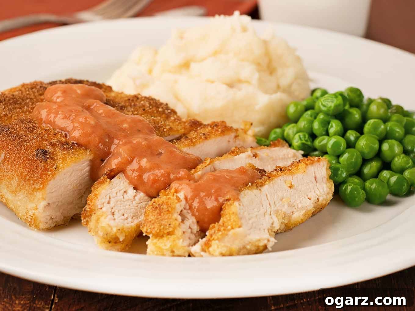 Crispy Pan-Fried Chicken with Tangy Tomato Gravy 3 Perfectly sliced, cornmeal-crusted pan-fried chicken breasts, generously topped with a rich Southern tomato gravy and served with creamy mashed potatoes and vibrant green peas – a hearty and comforting meal.