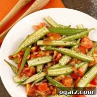 Aromatic Roasted Okra with Crispy Bacon and Sweet Tomatoes 3 A close-up of oven-roasted okra mixed with crispy bacon pieces and diced fresh tomatoes in a serving dish.