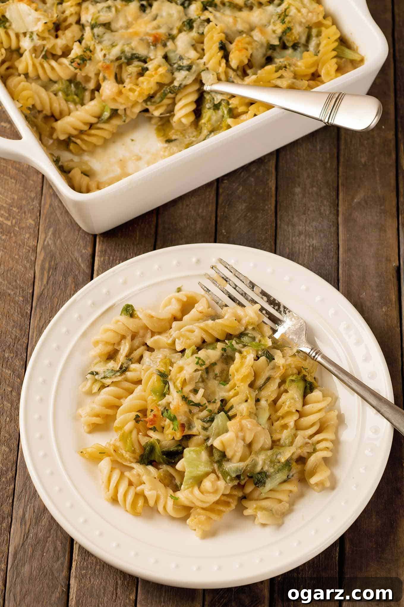 Cheesy Garlic Parmesan Pasta Bake 3 A single serving of pasta and greens with creamy garlic-Parmesan sauce on plate with the casserole in the background.