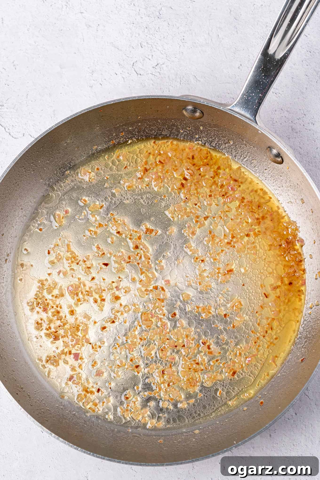 Crispy Crumb Cod Bake 4 A stainless steel frying pan with minced garlic and crushed red pepper flakes sautéed in olive oil and butter, releasing their aromatic flavors.