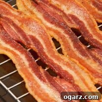 Crispy strips of baked bacon lined up on a rack inside a sheet pan.