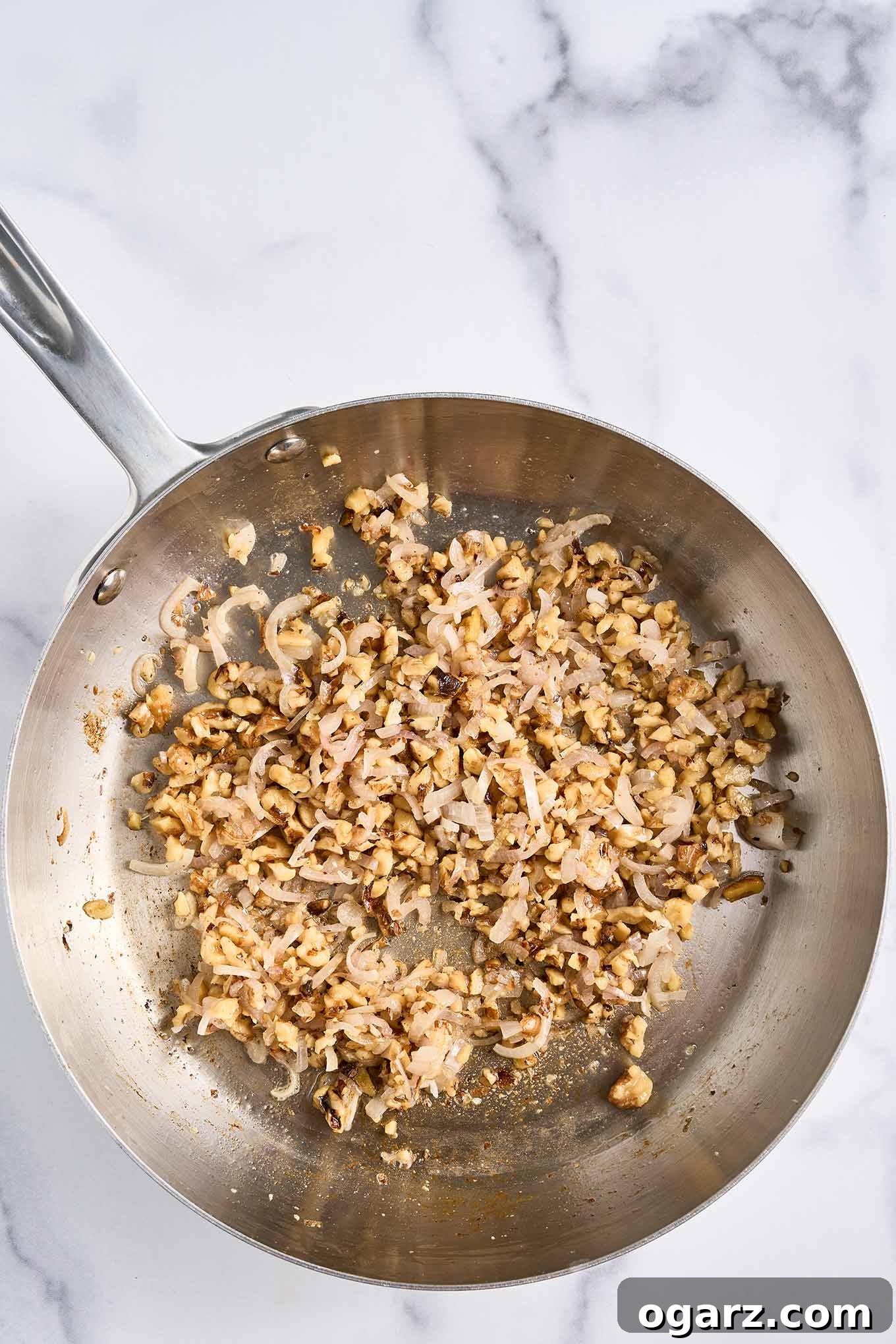 Finely sliced shallots and chopped walnuts are gently sautéing in a skillet with melted butter and oil, developing rich aromas and a golden hue for the topping.