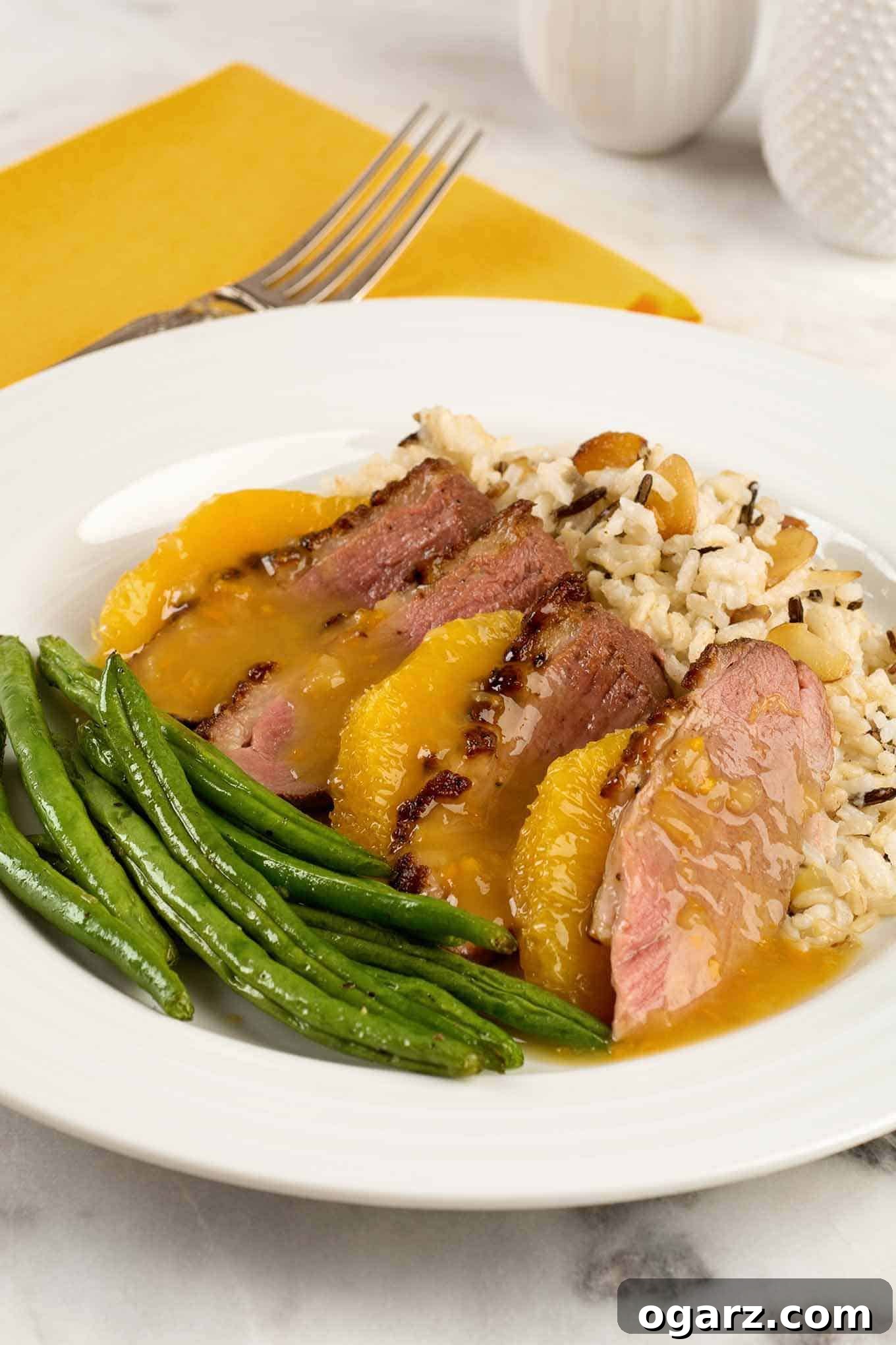 Orange Glazed Duck Breast 2 A plate with a serving of duck breast a l'orange; sliced duck breast, medium rare, orange supremes, rice pilaf, and green beans.