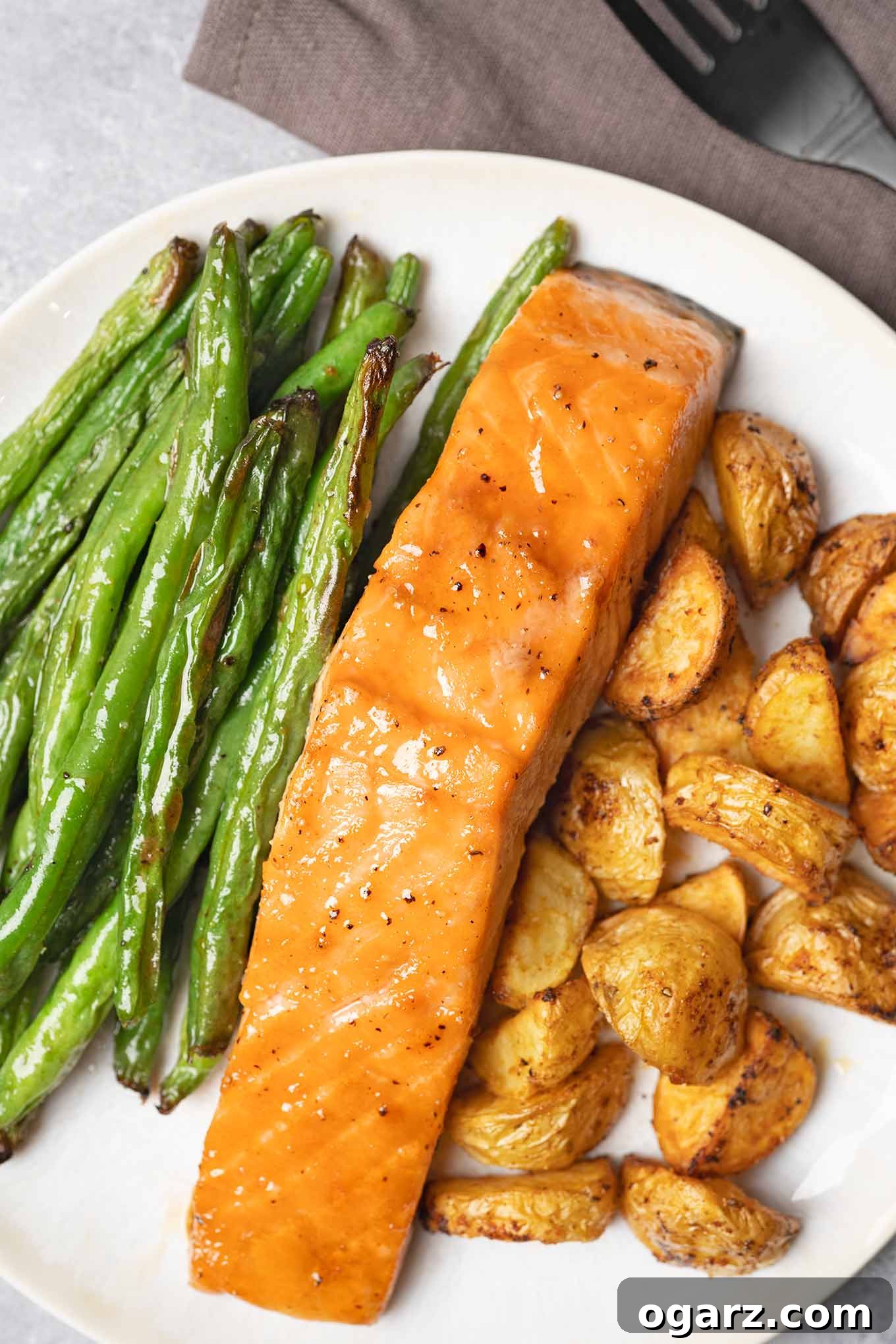 Fırından Tek Tepsi Lezzeti: Somon, Patates ve Taze Fasulye 2 A single serving of sheet pan salmon dinner including brown sugar-glazed salmon, roasted baby potatoes, and green beans.