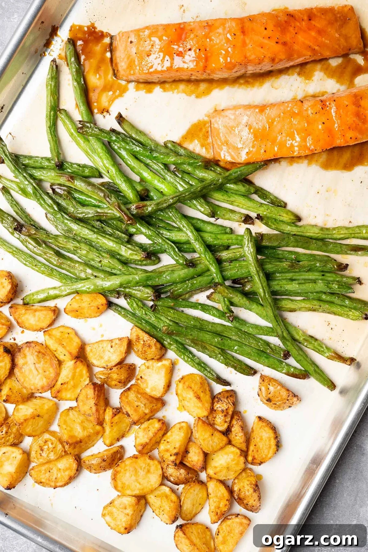 Fırından Tek Tepsi Lezzeti: Somon, Patates ve Taze Fasulye 4 Oven-roasted salmon dinner on parchment-lined sheet pan: glazed salmon fillets, green beans, and potatoes.