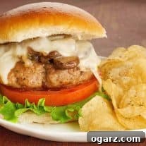 A close-up of a pan-seared turkey burger topped with sautéed mushrooms and onions and melted muenster cheese.