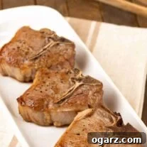 A serving plate with three beautifully seared lamb chops simply seasoned with olive oil, salt, and pepper.