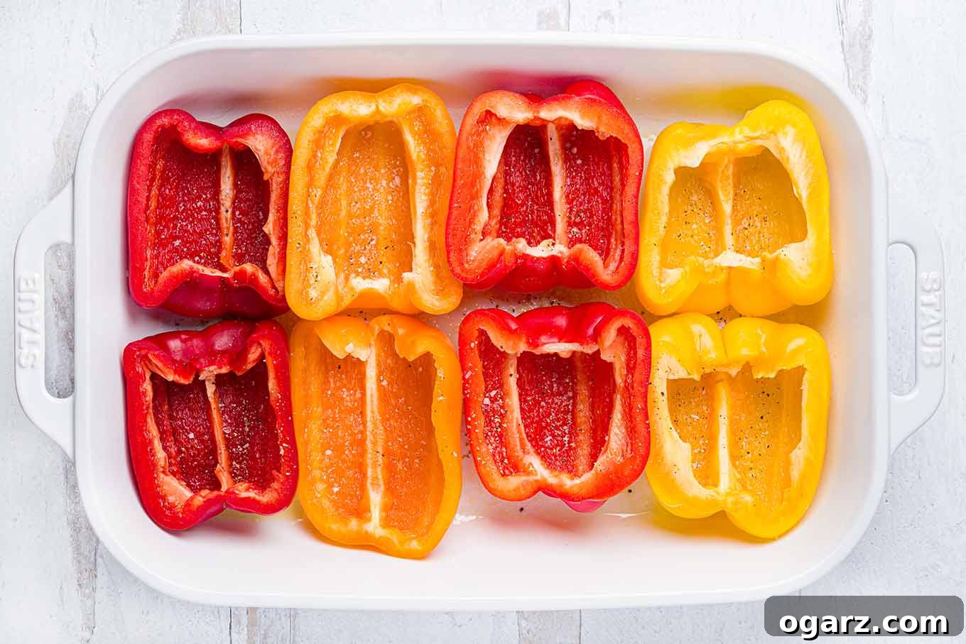 Greek Yemista 4 Red, yellow, and orange bell pepper halves arranged in a baking dish and ready for pre-baking as the first step in making Greek stuffed peppers.