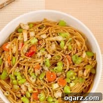 A bowl of whole wheat spaghetti tossed with edamame, stir-fried cabbage, sesame seeds and a light peanut sauce.