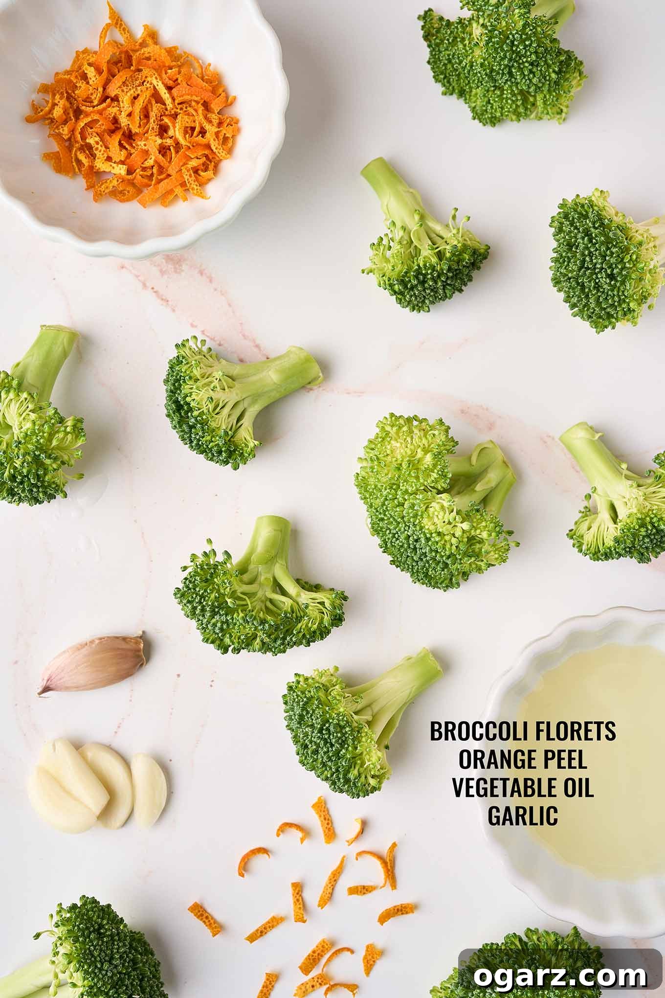 Zesty Orange Broccoli Sauté 3 Ingredients to make broccoli with orange peel on a marble background including broccoli florets, orange peel, and garlic.