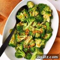 Zesty Orange Broccoli Sauté 6 Sauteed broccoli with citrusy orange peel, presented in a white oval bowl and accompanied by a black serving spoon.