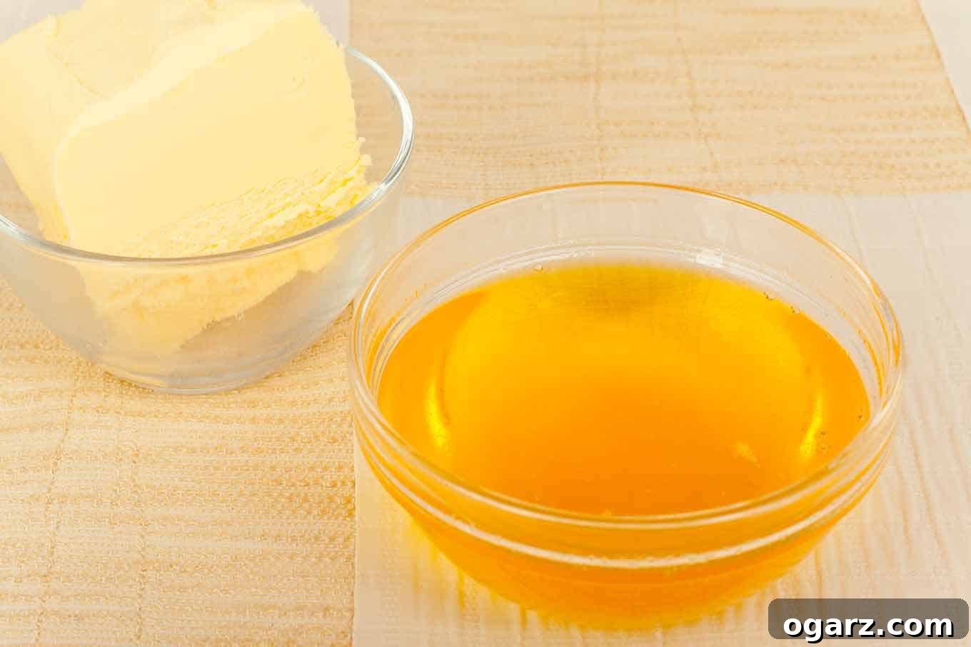 Crafting Your Own Golden Clarified Butter 2 A small, clear glass dish of golden clarified butter with a block of solid butter and a whisk in the background, illustrating the transformation process.