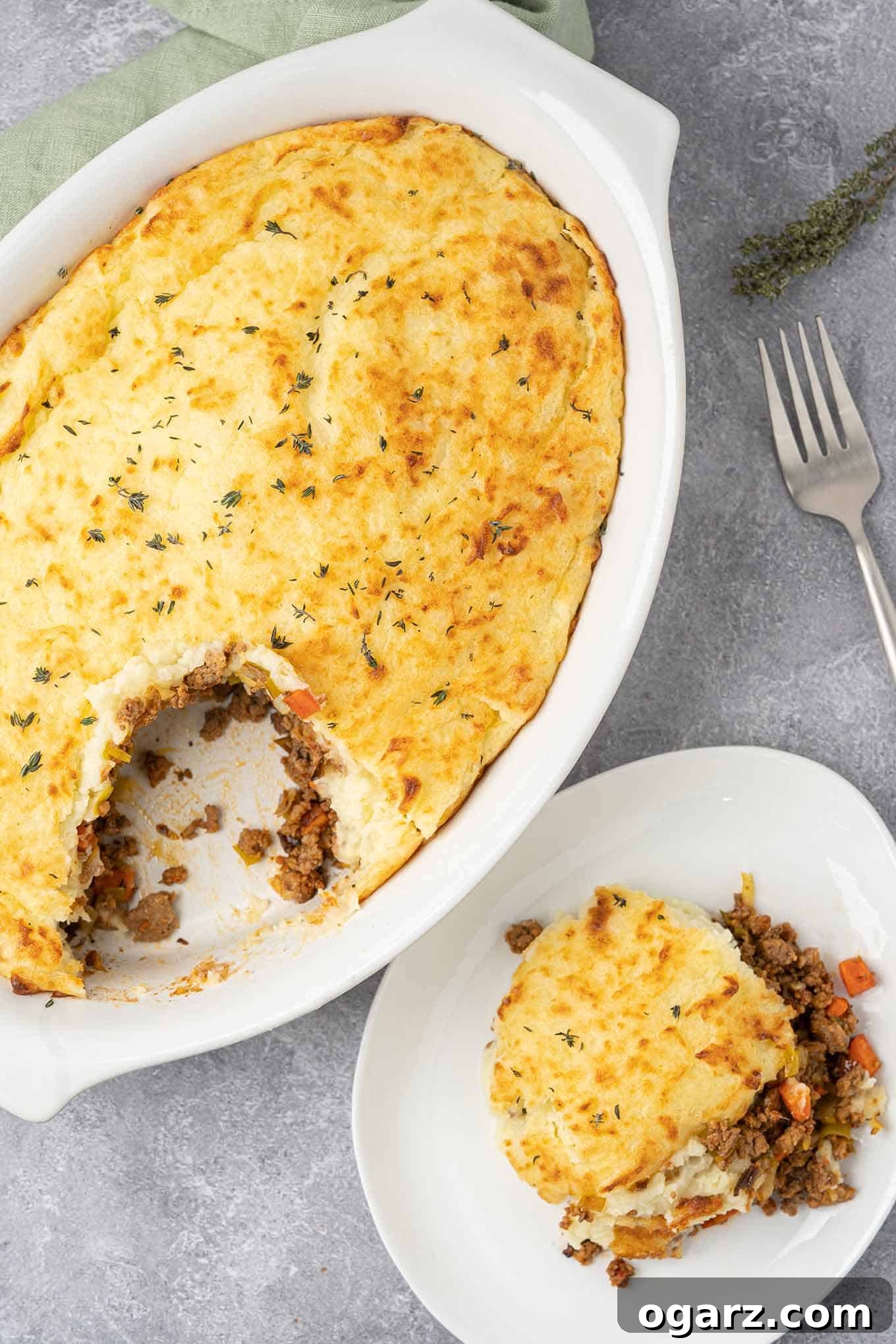 Classic Lamb Shepherd's Pie 2 A serving of traditional shepherd's pie with ground lamb on a plate with the casserole in the background.