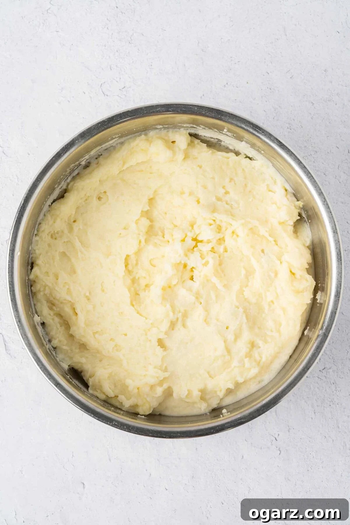 Classic Lamb Shepherd's Pie 4 A stainless mixing bowl filled with potatoes whipped with egg yolks, demonstrating the consistency for shepherd's pie topping.