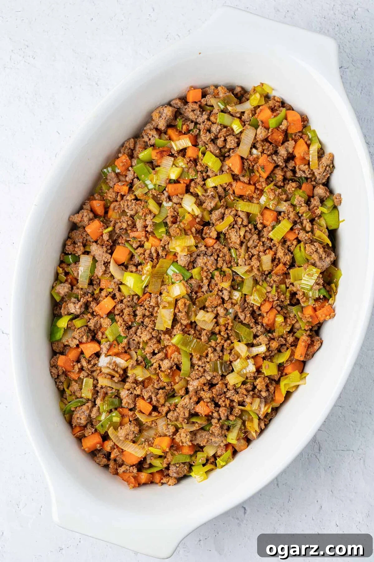 Classic Lamb Shepherd's Pie 5 Ground lamb combined with sautéed leeks, carrots, garlic, and thyme, spread in the bottom of a casserole dish.