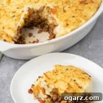 Classic Lamb Shepherd's Pie 9 A serving of Shepherd's Pie on a plate with the casserole in the background.