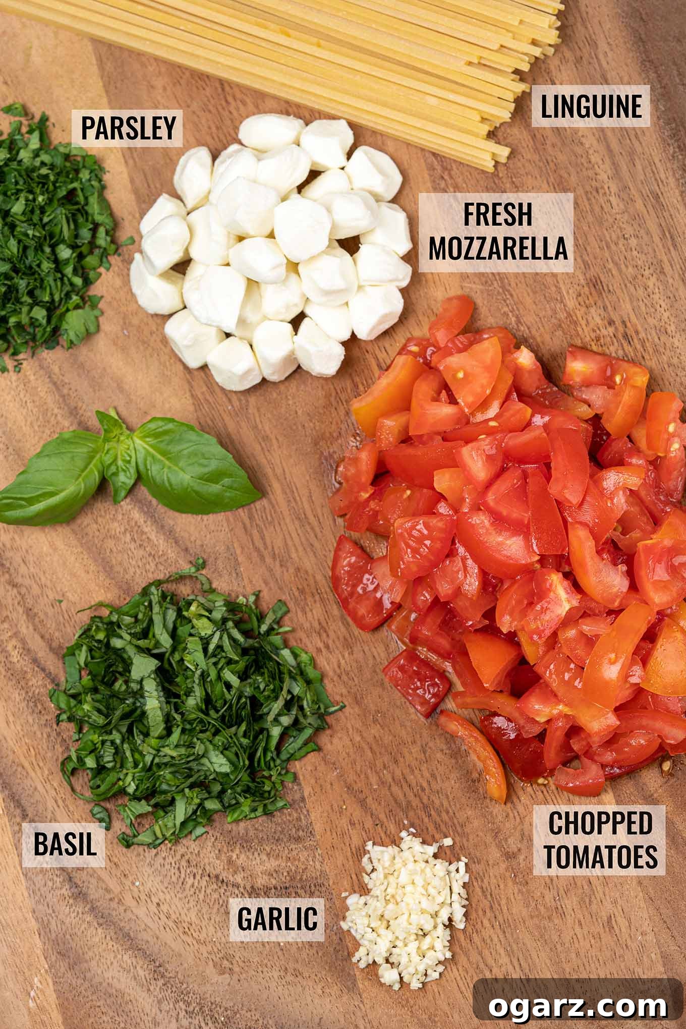 Vibrant Caprese Pasta 3 A labeled, overhead view of the ingredient for making caprese pasta including linguine, tomatoes, fresh mozzarella cheese, basil, parsley, and garlic.