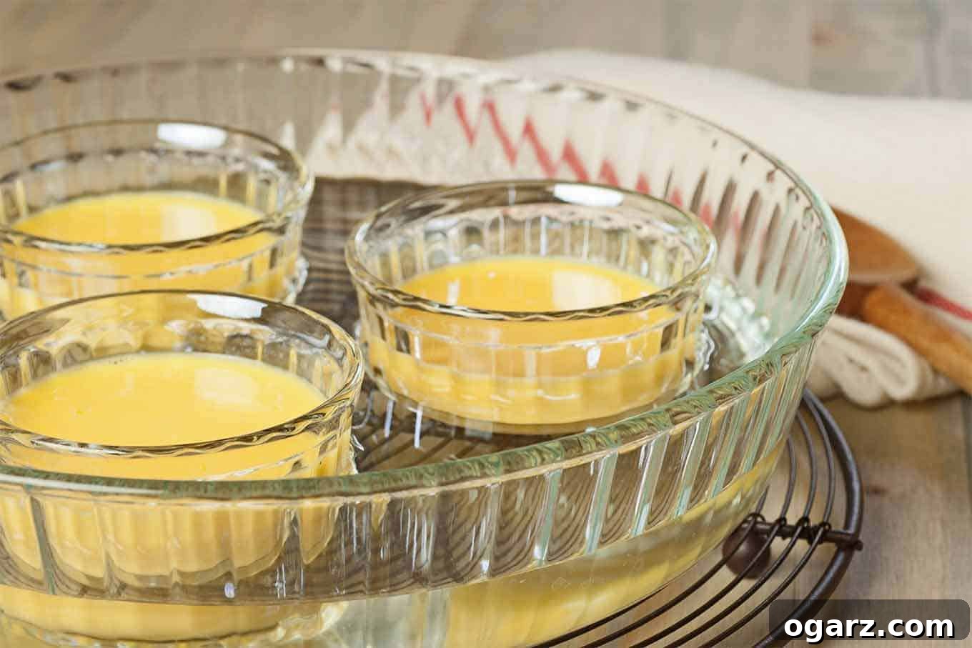 Mastering the Bain-Marie 2 A clear glass baking dish half filled with water, with clear custard cups set inside to illustrate how to cook using a water bath (bain-marie).