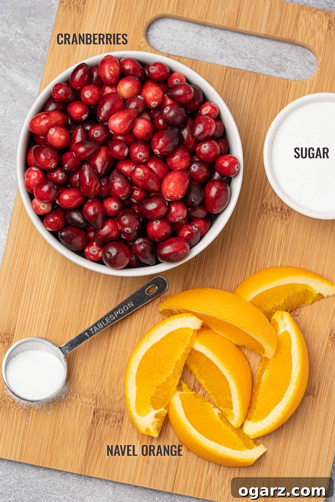 Effortless Cranberry Orange Zing 3 A labeled, overhead view of the ingredients needed to make cranberry orange relish including fresh cranberries, sugar, and navel orange.