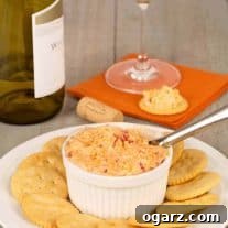 A small crock of homemade pimento cheese on a plate with crackers and a wine glass in the background.