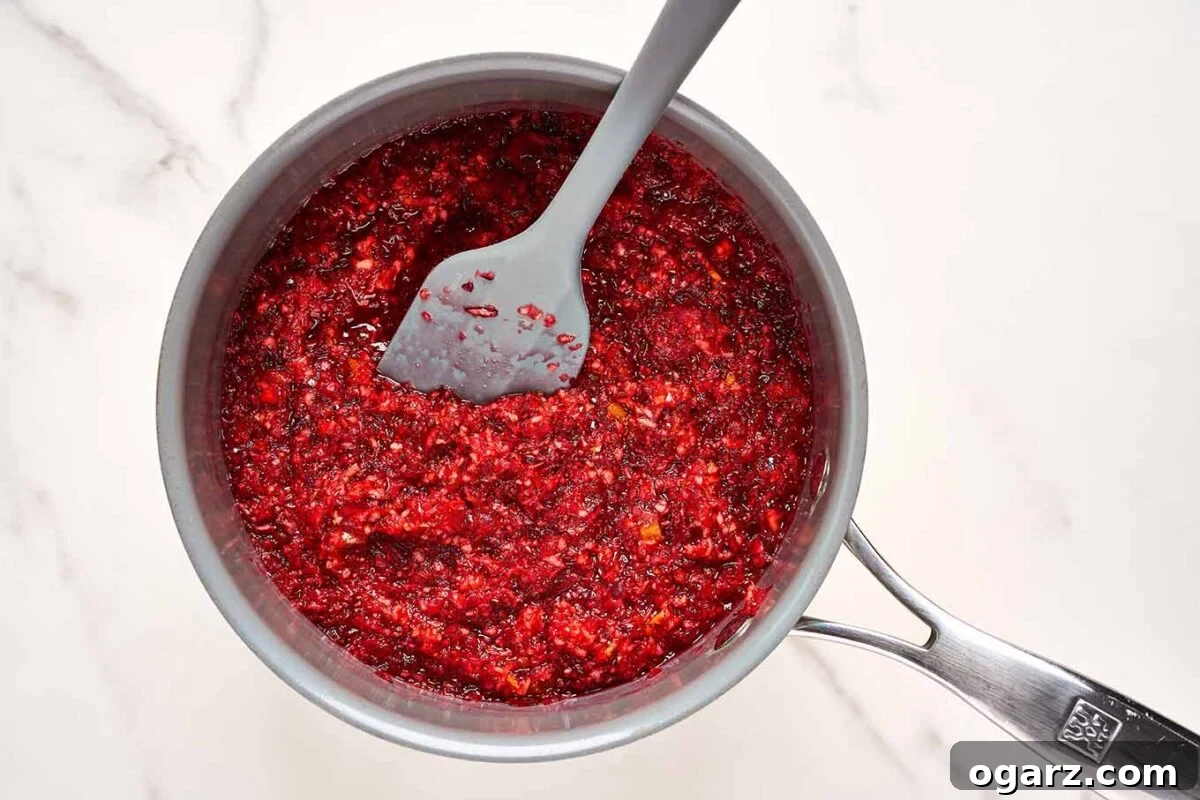 A saucepan filled with quick homemade cranberry jam for topping crescent roll brie bite appetizers.