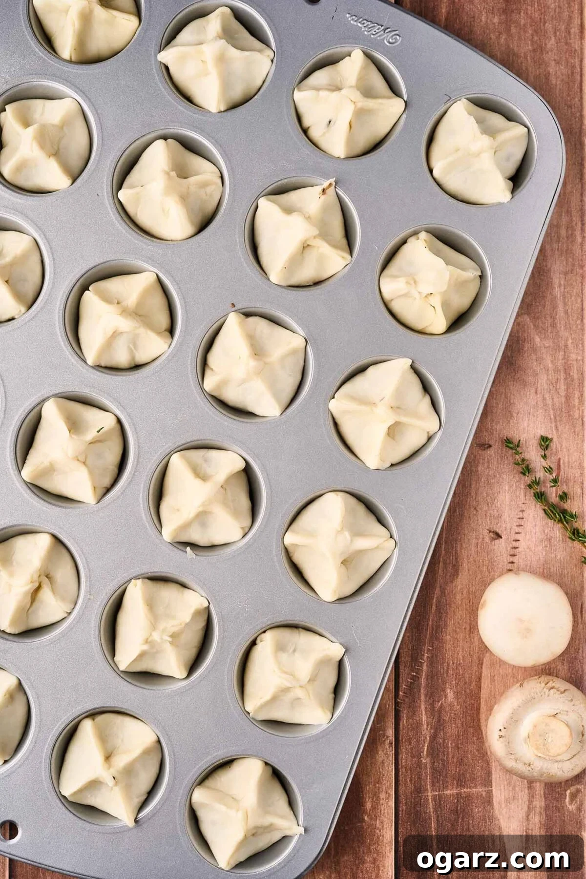 Umami Mushroom Puffs 7 A mini muffin tin with mushroom puffs ready for the oven, demonstrating how to pinch the tops to get the proper shape once baked.