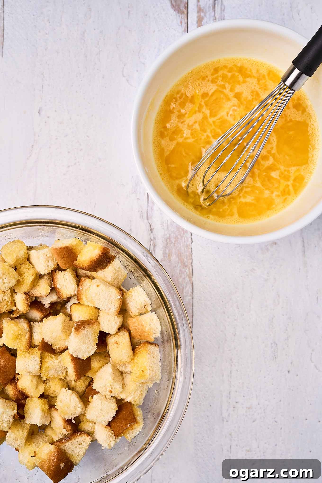 Golden Pineapple Gratin 4 A close-up shot of a mixing bowl, showcasing melted butter, well-drained crushed pineapple, and light, foamy beaten eggs being whisked together, ready to be folded into brioche bread cubes for a homemade scalloped pineapple casserole.