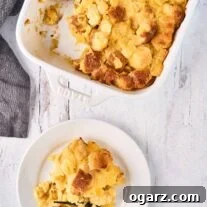 Golden Pineapple Gratin 7 Scalloped pineapple in white, oblong baking dish with one serving removed and placed on a plate to the side with a black fork, a gray napkin to the left.