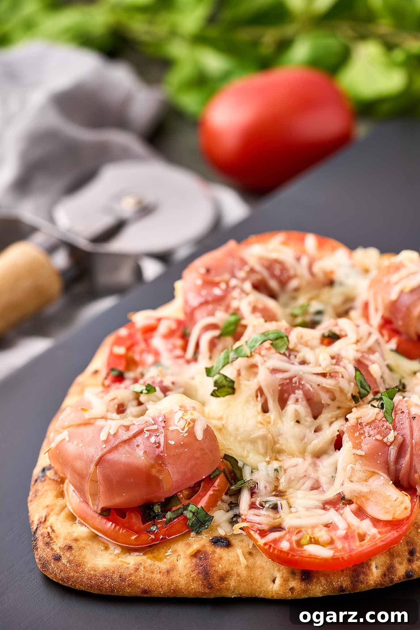 Crispy naan pizza topped with prosciutto-wrapped jumbo shrimp, sliced tomato, fresh basil, and melted mozzarella.