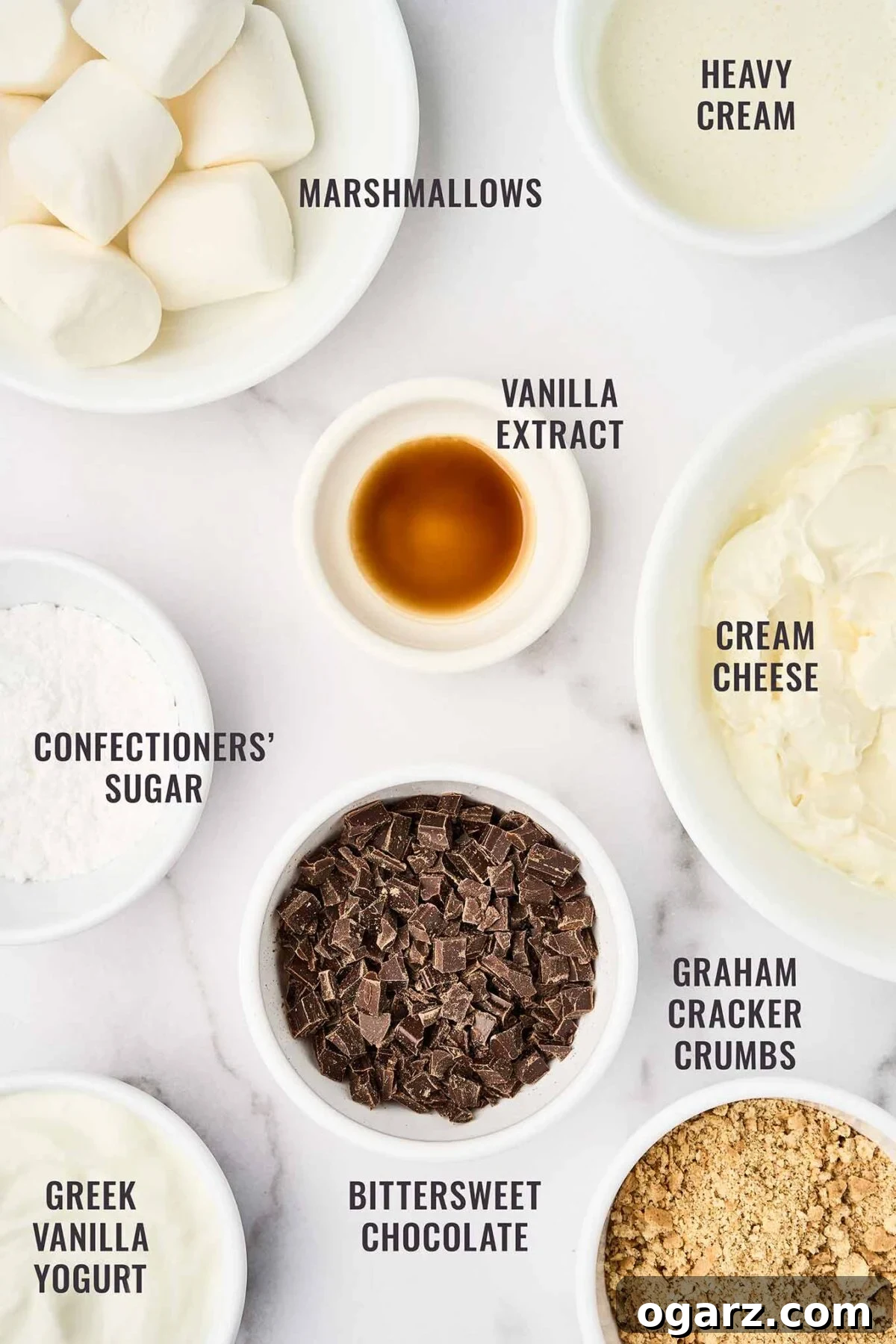 S'mores Parfaits 3 A labeled, overhead view of the ingredients for s'mores cheesecake parfaits: marshmallows, cream, cream cheese, vanilla, powdered sugar, bittersweet chocolate, graham cracker crumbs, and Greek vanilla yogurt.