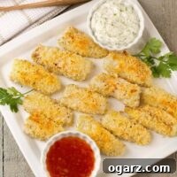 Panko-crusted, oven baked fish sticks on a serving plate with sweet Thai chili sauce and an Asian-style tartar sauce.