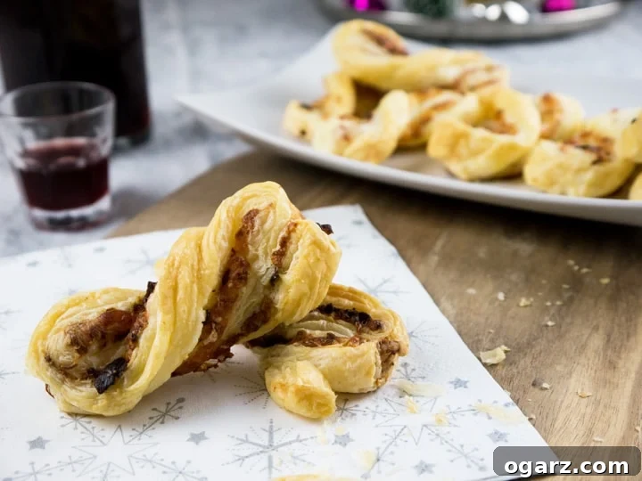 Three golden brown Bacon & Cheese Puff Pastry Twists arranged neatly on a wooden cutting board.