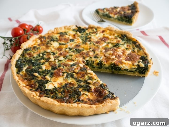A freshly baked spinach quiche with cheese and pine nuts, ready to be served for brunch or dinner.