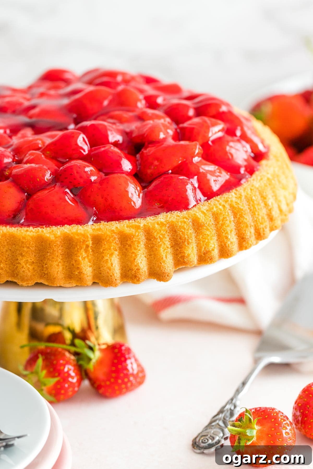 German Strawberry Kuchen 6 A beautifully decorated German Strawberry Cake, adorned with fresh berries and a glossy red glaze, presented on an elegant cake stand.