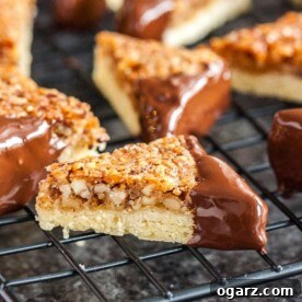 Elegant Nut Corners, with one corner dipped in luscious chocolate, arranged on a black cooling rack against a dark, inviting surface.