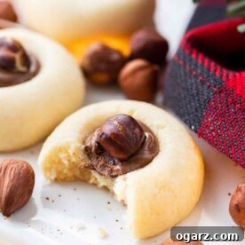 A delectable cookie generously filled with Nutella and topped with a whole hazelnut, showcasing its tempting rich center.