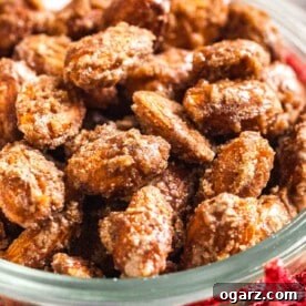 A clear glass bowl brimming with sweet, cinnamon-candied almonds, elegantly tied with a festive red ribbon, suggesting a perfect holiday gift.