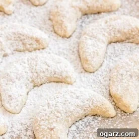 Delicate Vanillekipferl cookies generously dusted with a fine layer of powdered sugar, arranged invitingly.