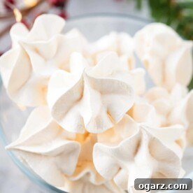 Light and airy Meringue Cookies, delicately arranged in a clear glass bowl, showcasing their crisp texture.