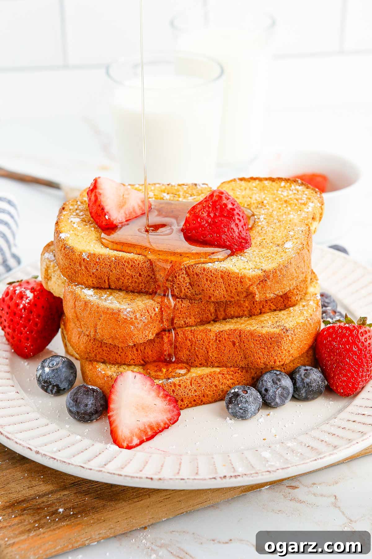 Syrup being poured over golden-brown air fryer French toast garnished with fresh berries.