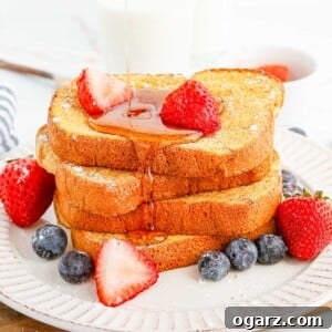 Syrup being poured over french toast garnished with berries.