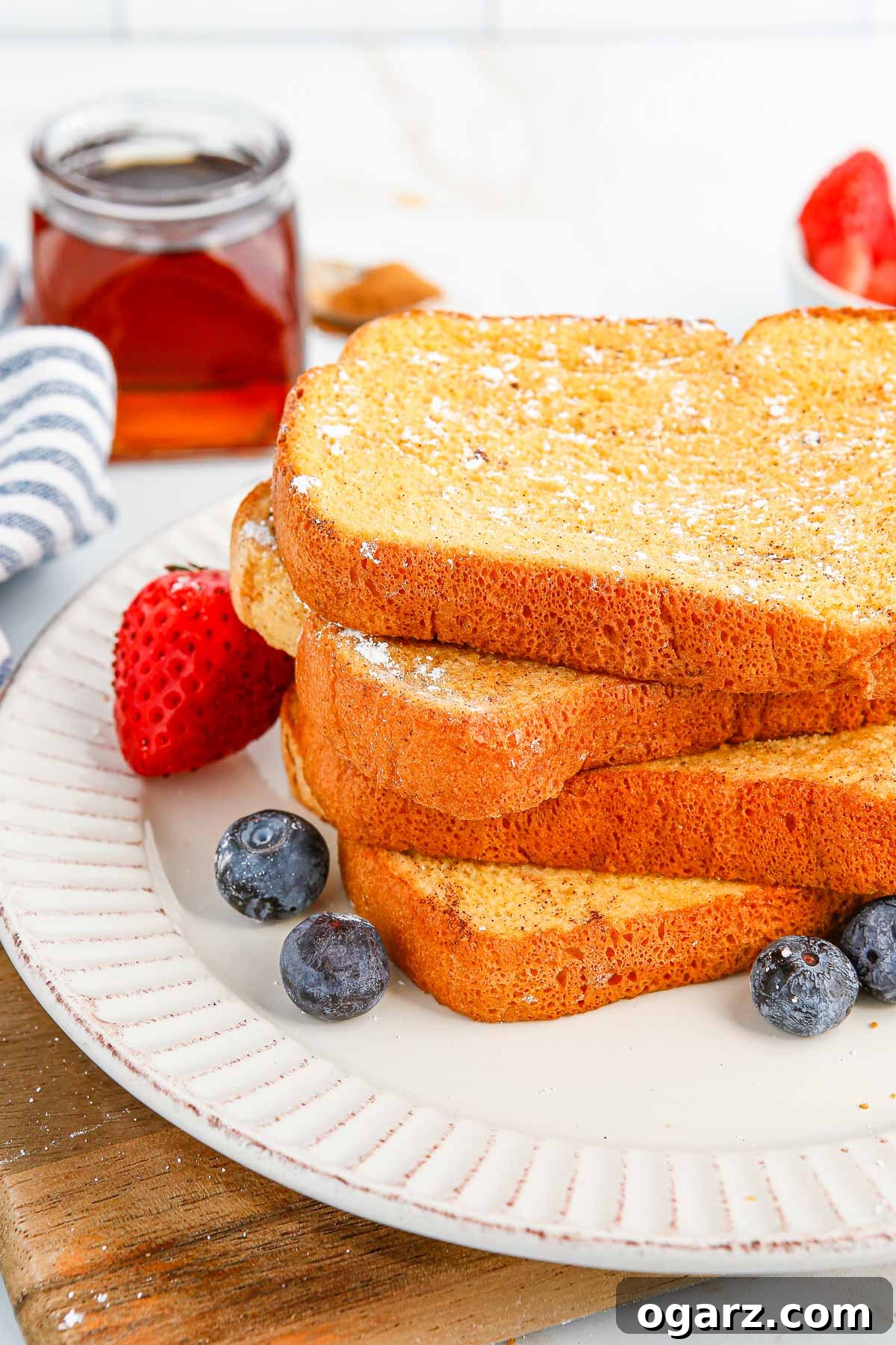 A stack of beautifully golden air fryer French toast on a white plate, ready to be enjoyed.