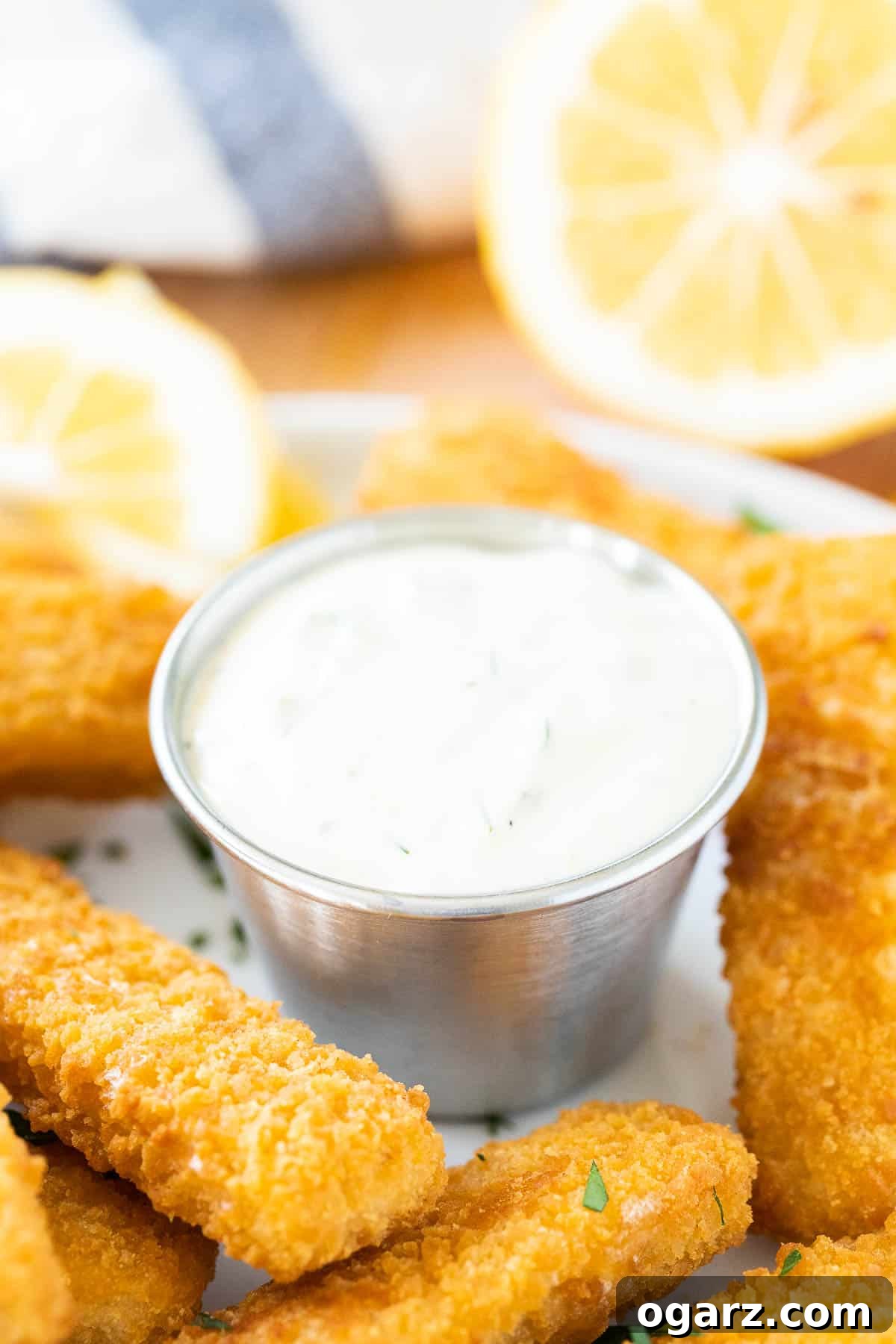 Fresh & Zesty Homemade Tartar 4 A small metal bowl of homemade tartar sauce sits next to crispy fish sticks and a lemon wedge, ready for dipping.