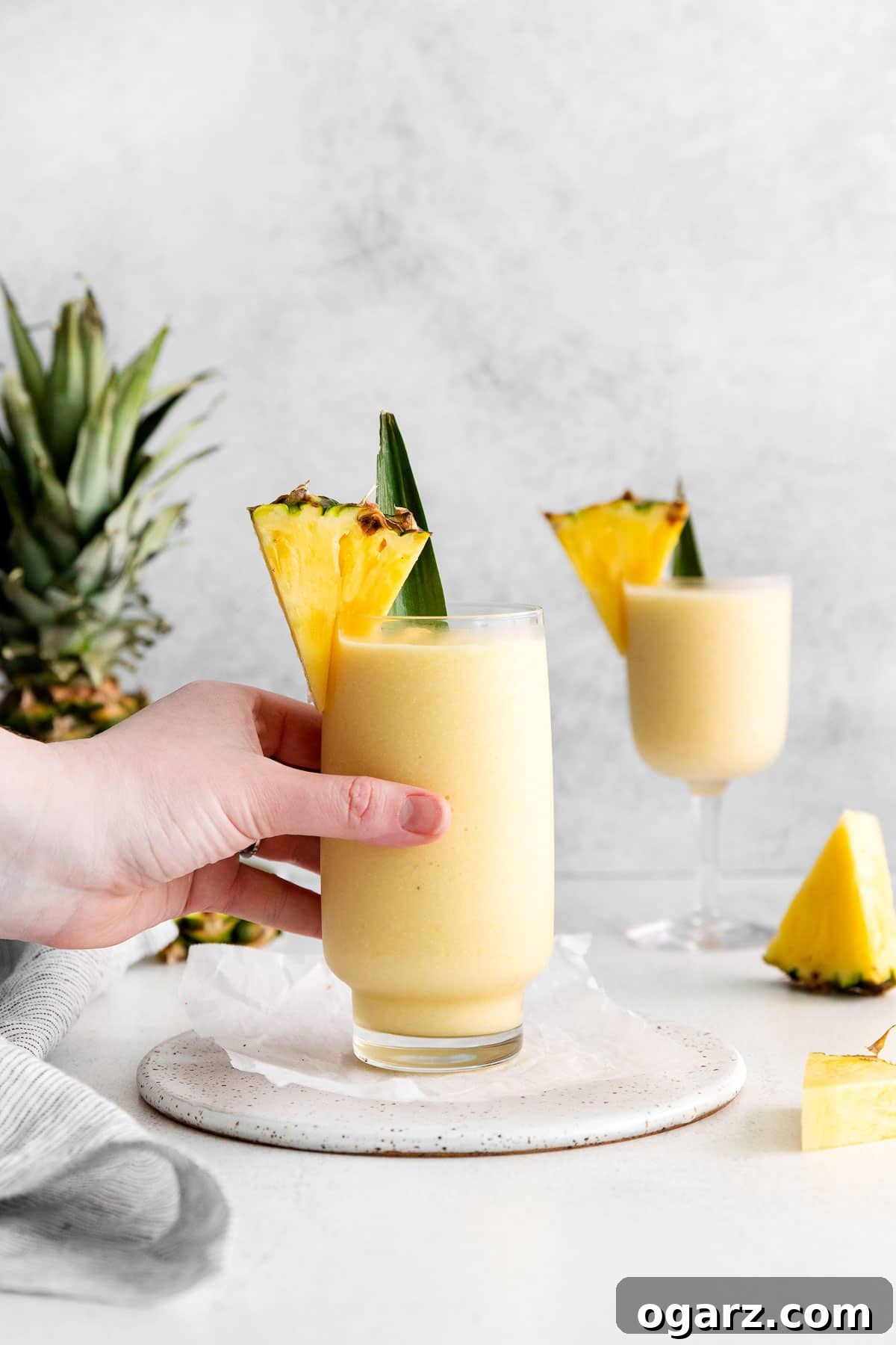 Pina Colada Mocktail 6 A female hand reaching for a large glass.