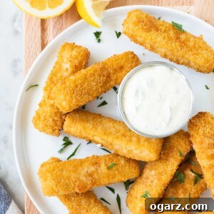 Fish sticks on a white plate garnished with parsley on a wooden board.